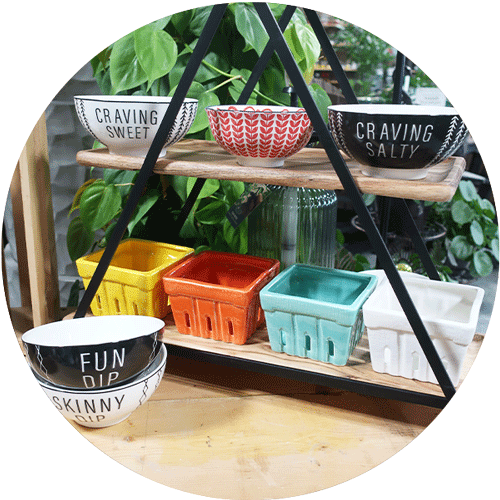 A two tier tabletop shelf with both black and white and colorful serving bowls on both shelves.